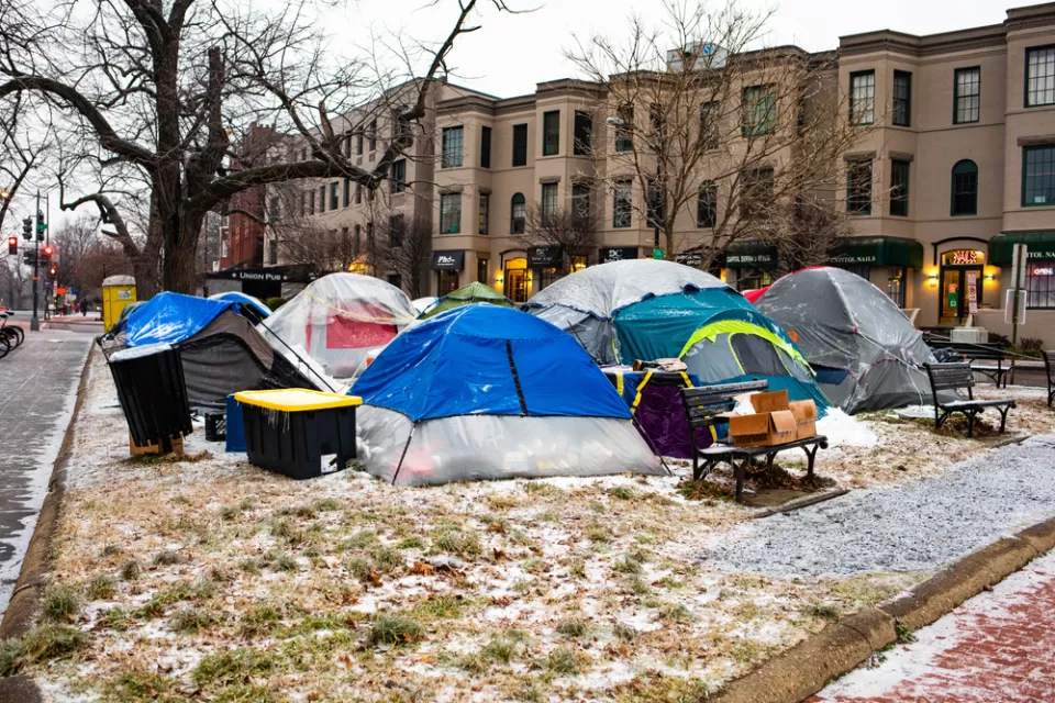 Group of tents and bins used by unhoused people in Washington, D.C. park with snow